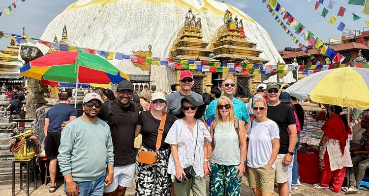 Grupo de personas frente a la Estupa de Boudhanath con banderas de oración.