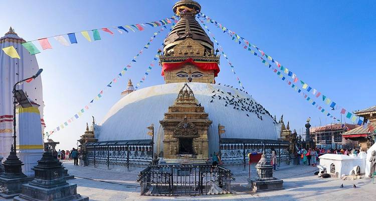 Estupa de Swayambhunath con banderas de oración y palomas.