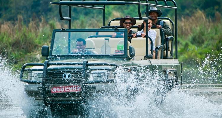 Turistas emocionados en un jeep descapotable salpicando a través del agua.