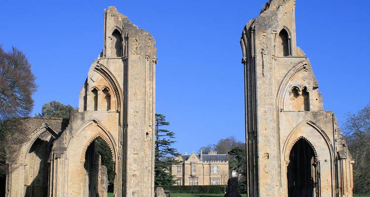 Ruines de l'abbaye de Glastonbury en Angleterre avec un bâtiment historique en arrière-plan.