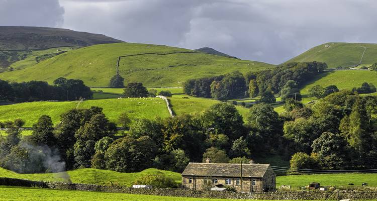 Countryside rural landscape with a stone house and green hills.