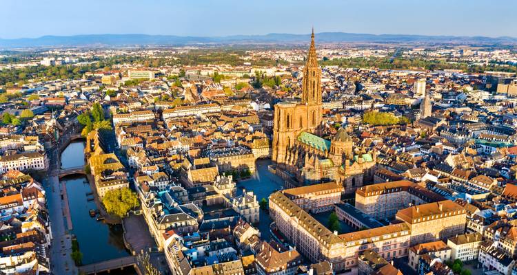 Impresionante vista aérea de la Catedral de Notre-Dame de Estrasburgo elevándose sobre el denso casco antiguo al amanecer.