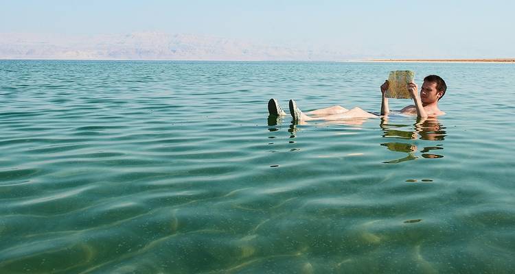 Person floating in the Dead Sea reading a newspaper.