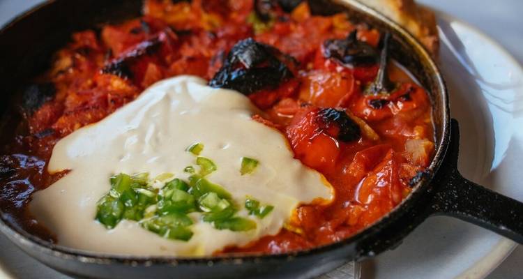 Skillet with cooked red dish topped with cream