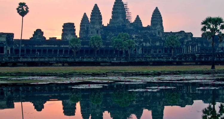 Silhouet van Angkor Wat bij zonsondergang met een weerspiegeling in het water.