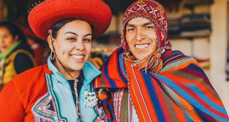 Two people wearing traditional Andean clothing smiling at the camera.