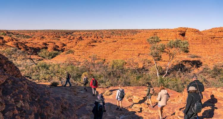 Les visiteurs font de la randonnée parmi les dômes de grès rouge frappants et les ravins sous un ciel bleu dégagé à Kings Canyon.