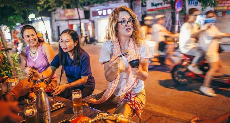 Street food scene with people enjoying local dishes at night.