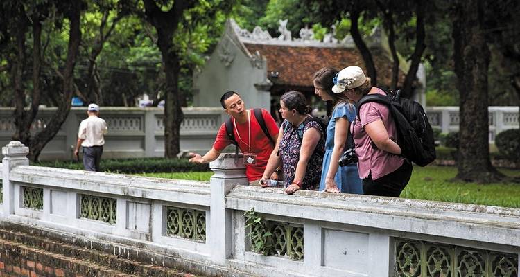 Tour group listening attentively to a guide at an outdoor site.