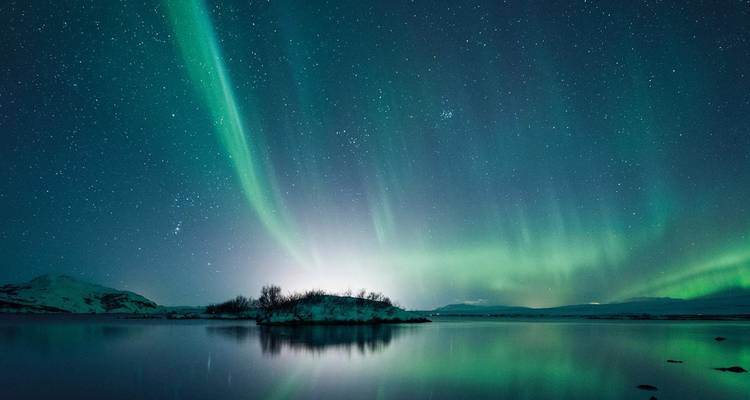 Aurores boréales au-dessus d'un lac calme avec ciel étoilé