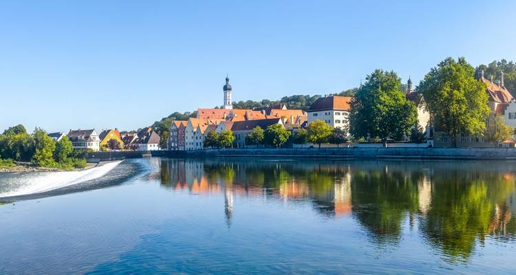 Vue panoramique d'une rivière avec des bâtiments se reflétant dans l'eau.