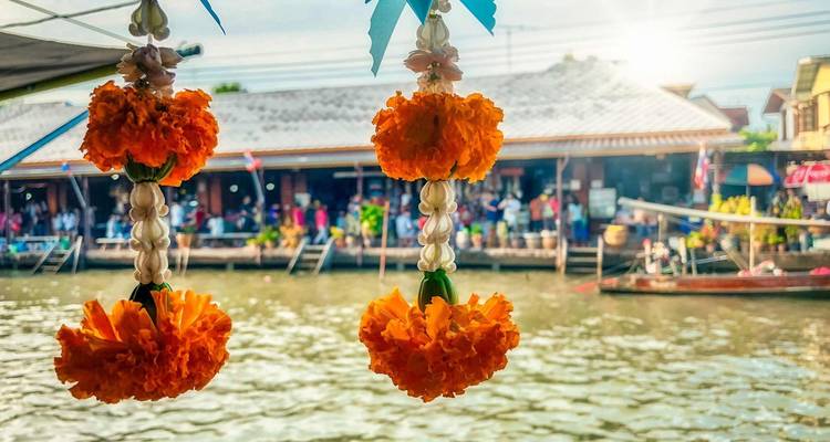 Close-up of orange flowers and scenery of a riverfront market in the background.