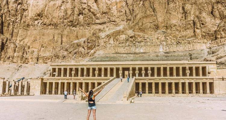 Persona parada frente a la fachada de un gran templo en el desierto.