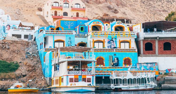 Kleurrijke gebouwen langs de rivieroever met boten.