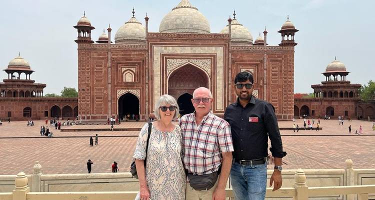 Drei Personen posieren mit einem historischen Gebäude im Hintergrund