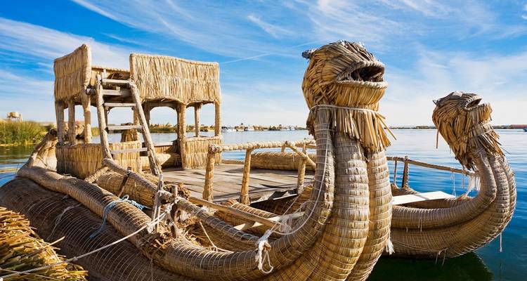 Barca tradicional de totora con proa en forma de dragón flotando en las aguas tranquilas del Lago Titicaca.
