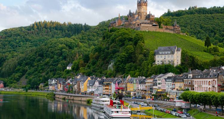 Pintoresco pueblo ribereño de Cochem con casas coloridas bajo un castillo en la colina que domina el tranquilo río Mosela.