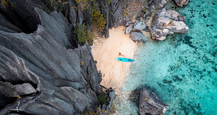 Voyageur solitaire se prélassant sur une plage isolée aux eaux turquoise et aux falaises escarpées.