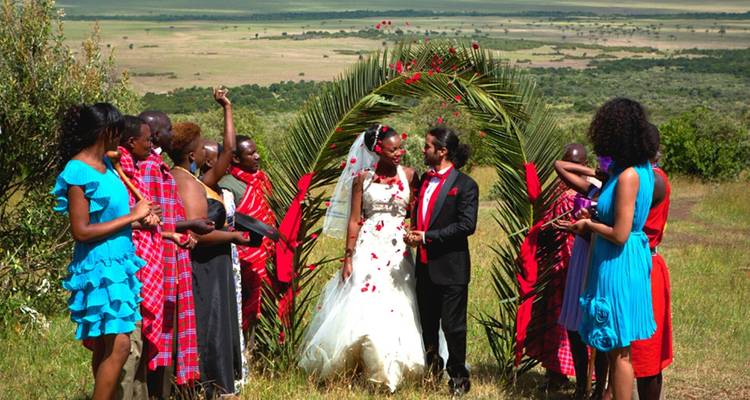 Une cérémonie de mariage avec un couple et des Maasaï en tenue traditionnelle, avec une vue panoramique en arrière-plan.