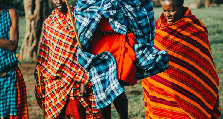 Hommes masaï en tenue traditionnelle colorée sautant en l'air.