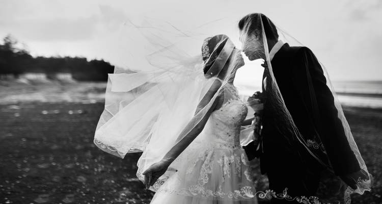Une silhouette de mariée et marié avec un arrière-plan de plage.