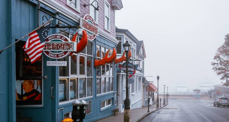 Rue du Maine brumeuse avec des enseignes de restaurant de homard et un drapeau américain lors d'une matinée tranquille.