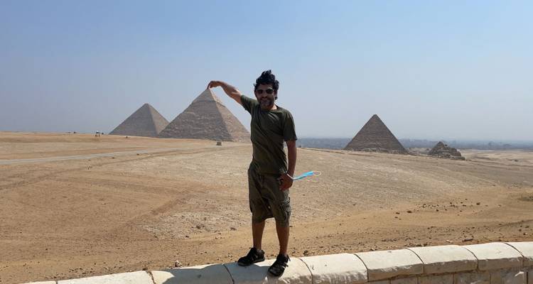 Person posiert spielerisch mit den Pyramiden im Hintergrund.