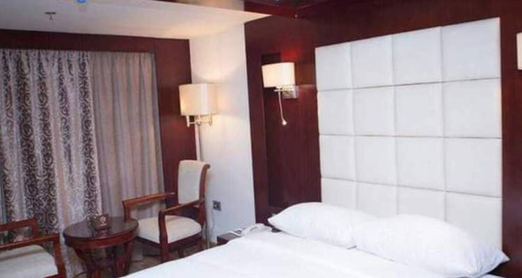 Gemütliche Kreuzfahrtschiff-Kabine mit Doppelbett, dunklen Holzakzenten und einem Panoramafenster mit Vorhängen.