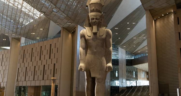 Statue d'un pharaon de l'Égypte antique dans un musée moderne.
