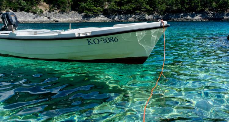 Bateau flottant sur des eaux turquoise claires avec un arrière-plan rocheux.