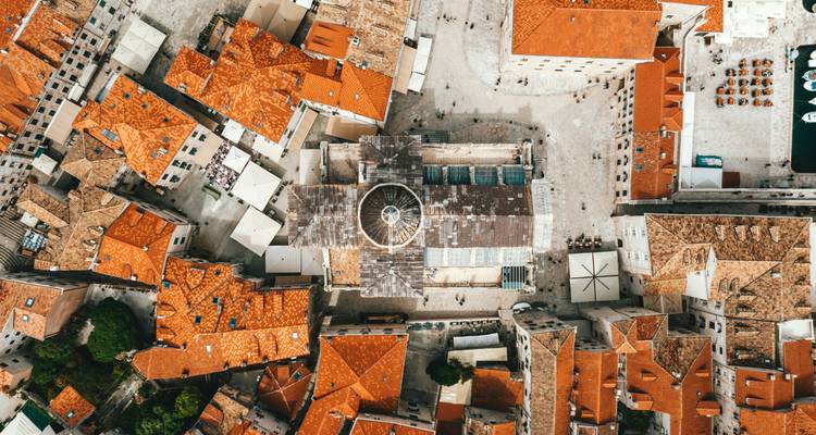 Vue aérienne d'une ville avec des toits de tuiles rouges et un dôme central.