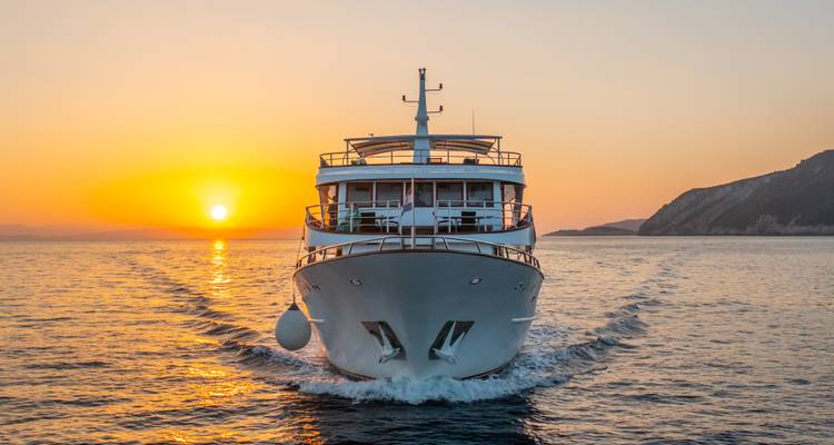 Vooraanzicht van een boot die naar de zonsondergang vaart.