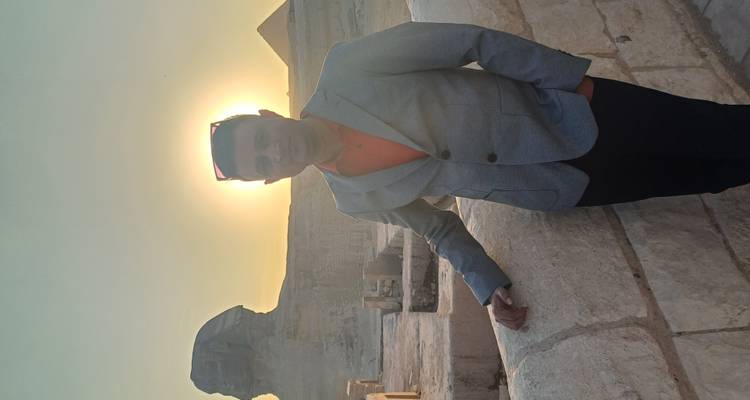 Persona posando con gafas de sol frente a una pirámide.