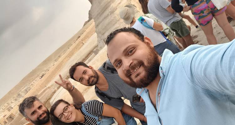 Selfie de amigos con un grupo sonriente en un sitio histórico.