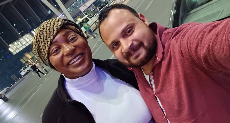 Pareja sonriente tomándose una selfie en un espacio público interior.