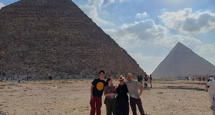 Una familia capturando un momento frente a las Grandes Pirámides bajo un cielo brillante.