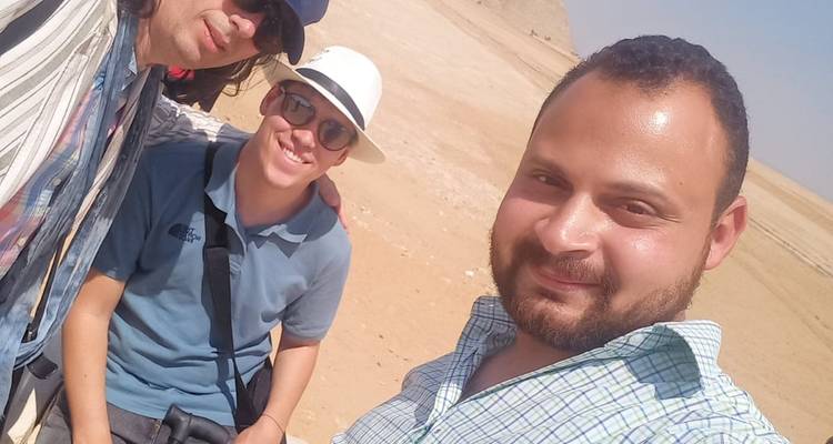 Tres personas posando para una foto frente a un fondo desértico.
