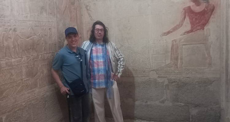 Dos personas paradas dentro de un templo con grabados antiguos.