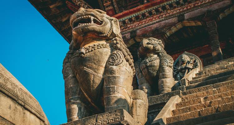 Statues de lions sur les marches du temple avec des sculptures complexes.