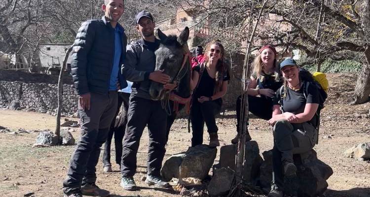 Grupo de excursionistas con un burro posando bajo los árboles en un entorno rural.