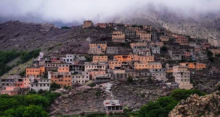 Pueblo de montaña brumoso con numerosos edificios dispersos en una ladera.