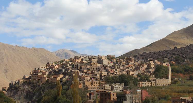 Pueblo de montaña con casas muy juntas bajo un cielo azul con nubes.