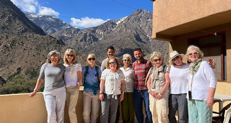 Grupo de turistas mayores sonriendo y posando con montañas de fondo.