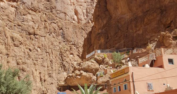 Edificios tallados en un acantilado con terreno rocoso y cielo despejado.