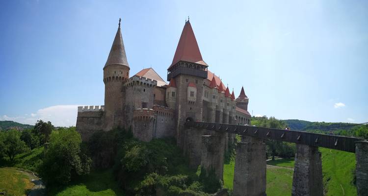 Gran castillo histórico con torres y un puente de madera.