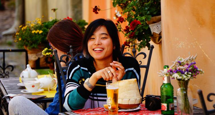 Mujer joven disfrutando de una bebida en un café pintoresco.