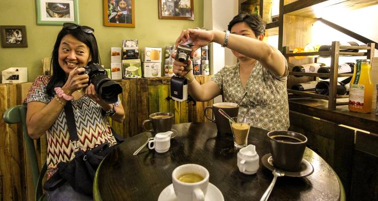 Mujeres fotografiando tazas de café en un ambiente acogedor de cafetería.
