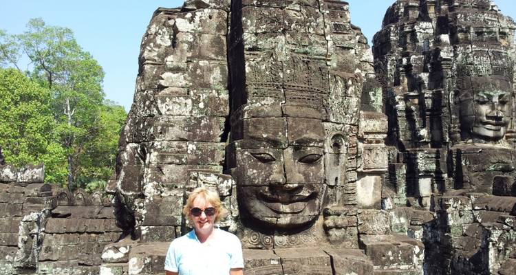 Toerist die poseert bij de grote gezichten van de Bayon-tempel.
