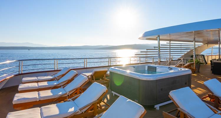 Dek van een cruiseschip met ligstoelen en een hot tub.
