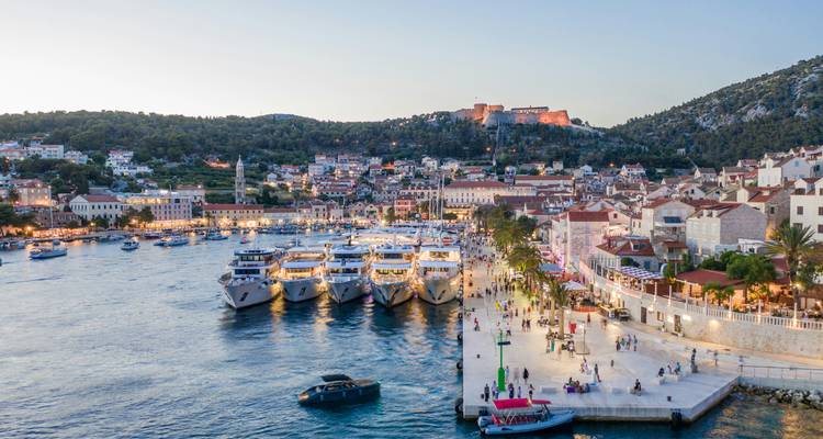 Une ville côtière avec des yachts et une forteresse au coucher du soleil.